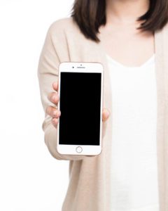 Image of woman holding up a cell phone learning how to grow Pinterest followers. 