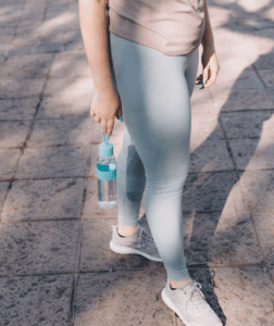 Image of woman in work out apparel standing outside looking after her health. 