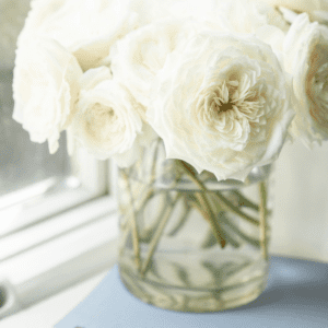 Flowers in a glass vase sitting on a desk.