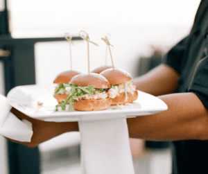 Image of food being served, these are small sliders and there are 4 on a white plate.