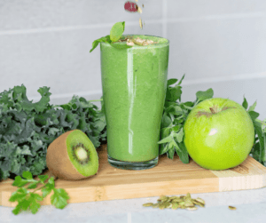 Image of a green smoothie with kiwi and apple beside showing how for fibre snacks you can make smoothies packed with fibre! 