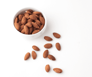 Image of a bowl of almond with a couple outside the bowl sitting on the counter showing nuts as a great high fibre snacks idea!