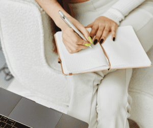 Image of woman making a list on a blank page showing how to plan your week to be productive. 