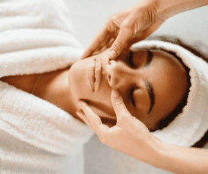 A woman laying down and getting a facial massage. 