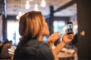 Image of woman on a phone blowing a kiss to partner.