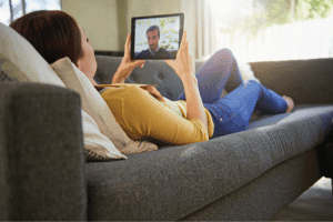 Image of woman laying on couch holding an ipad.
