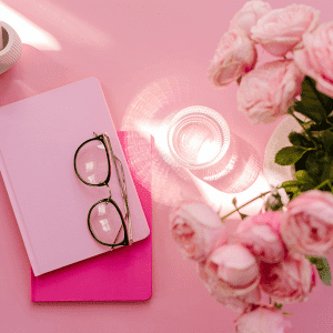 Image of blush pink work items such as journal glasses and roses. 