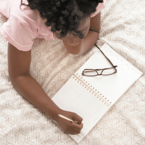 Image of woman laying in bed journaling for tips to get to sleep.