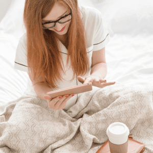 Woman on tablet with coffee before bed showing what can cause sleep difficulties. 