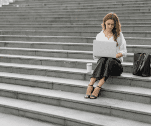 Image of woman sitting on cement stairs working on a laptop about pinterest pin design.